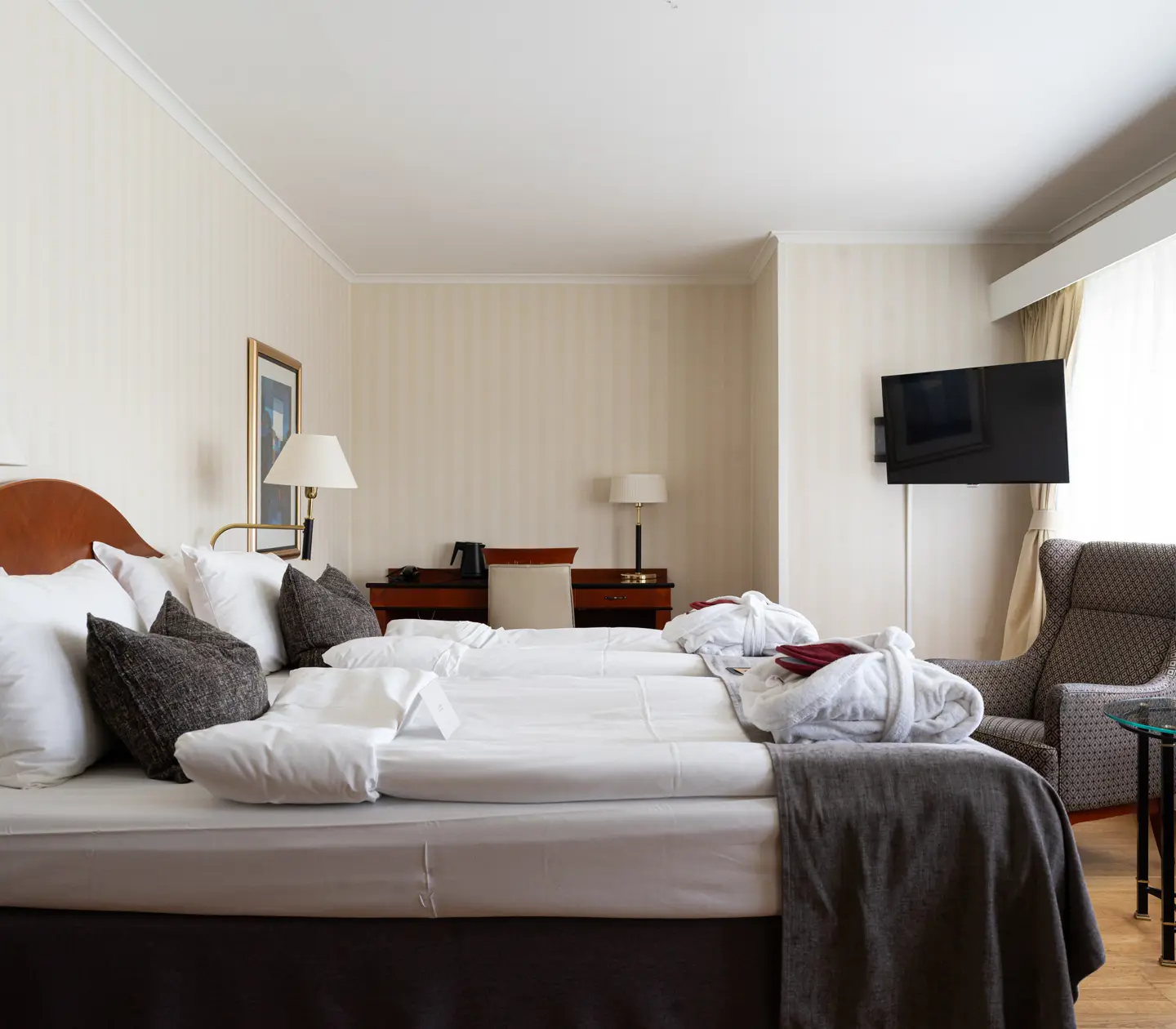 Mysigt hotellrum med morgonrock på säng, garderob och fåtöljer