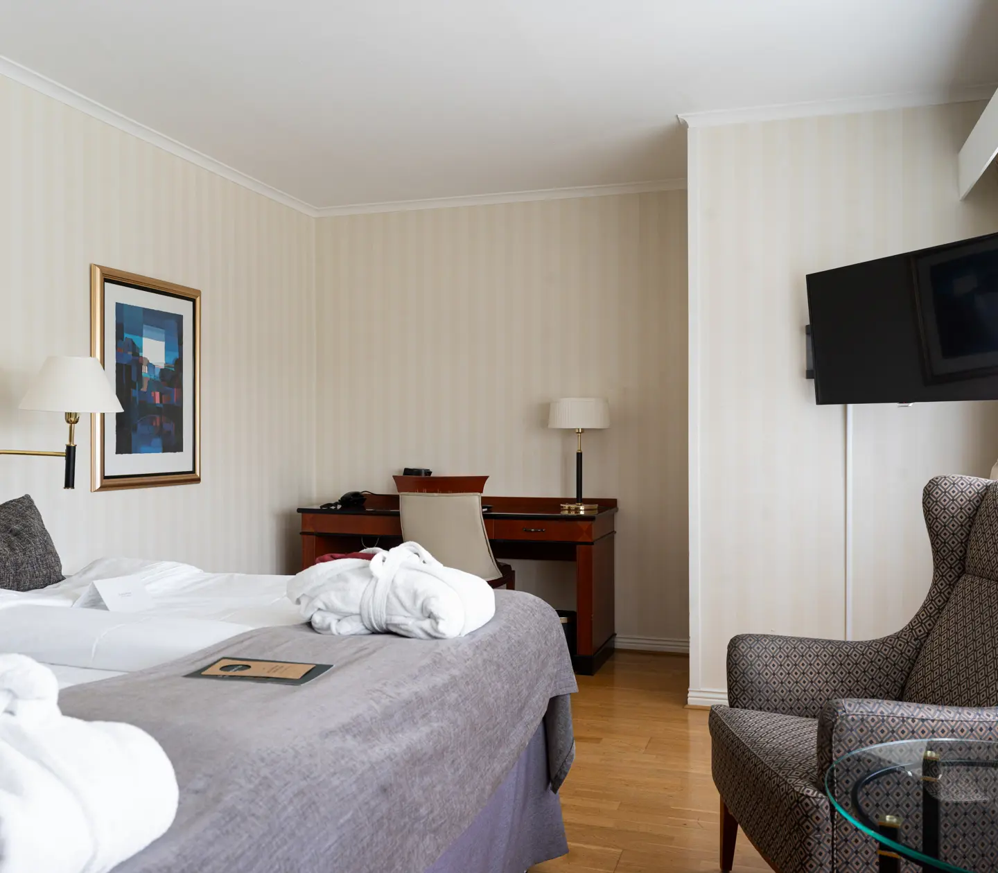 Mysigt hotellrum med garderob, fåtölj och rund spegel
