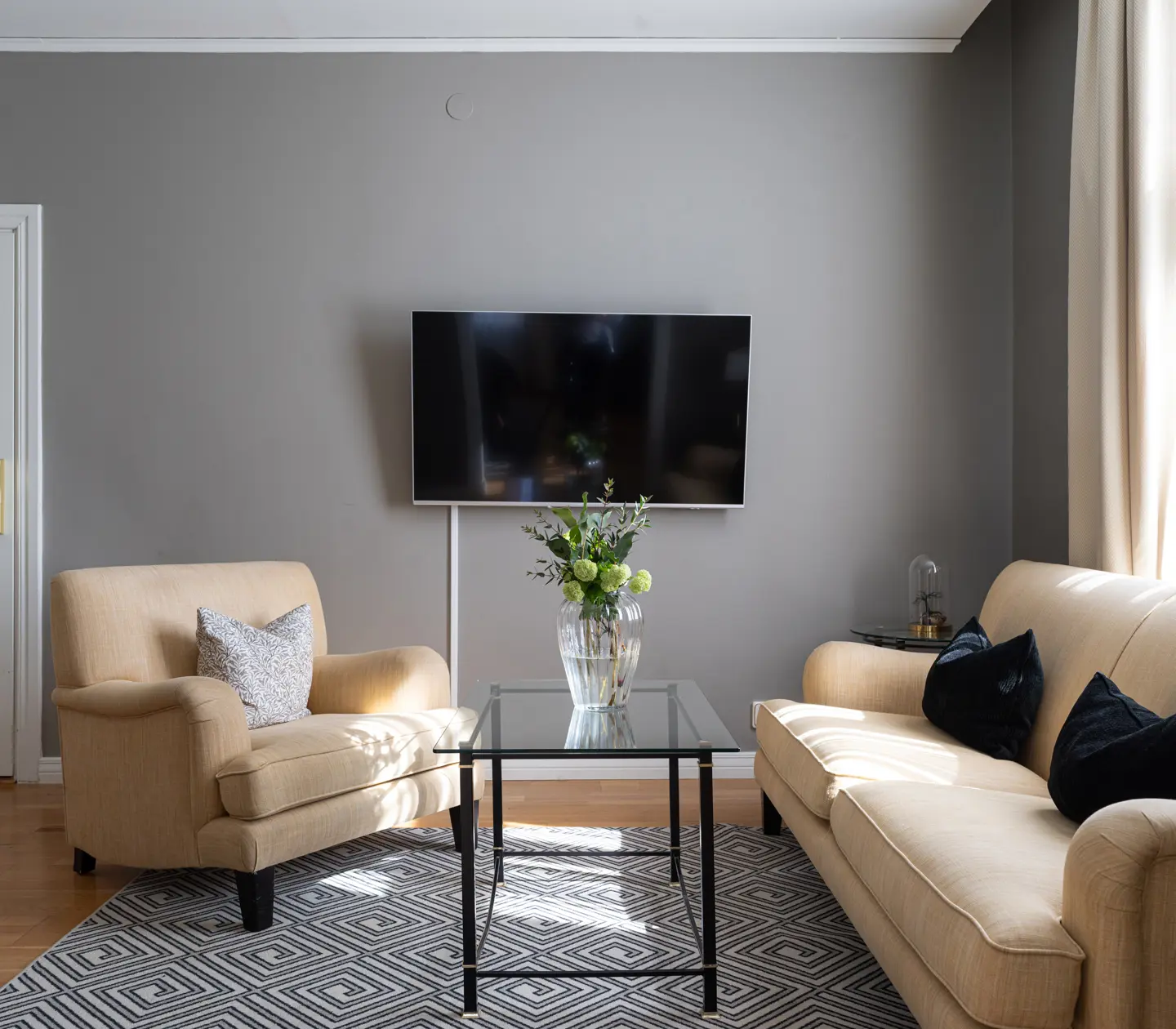 Mysig svit med grå soffgrupp, tv och skrivbord