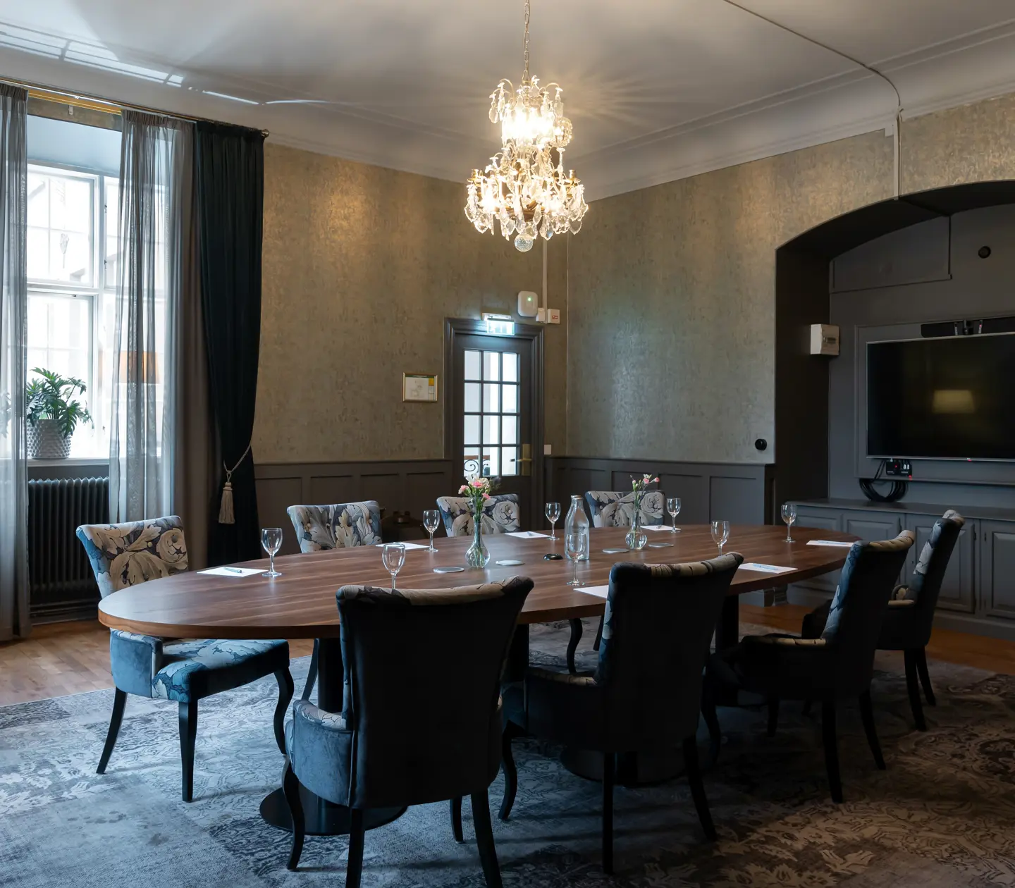 Conference room with round table, TV and crystal chandelier