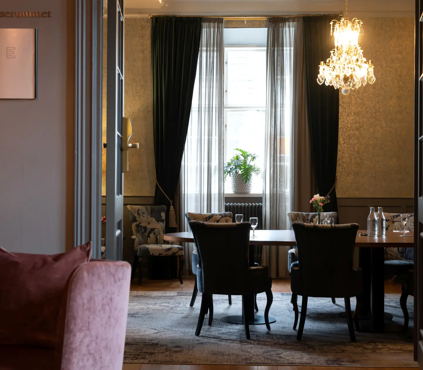 Open door to conference room with round table, window and crystal chandelier