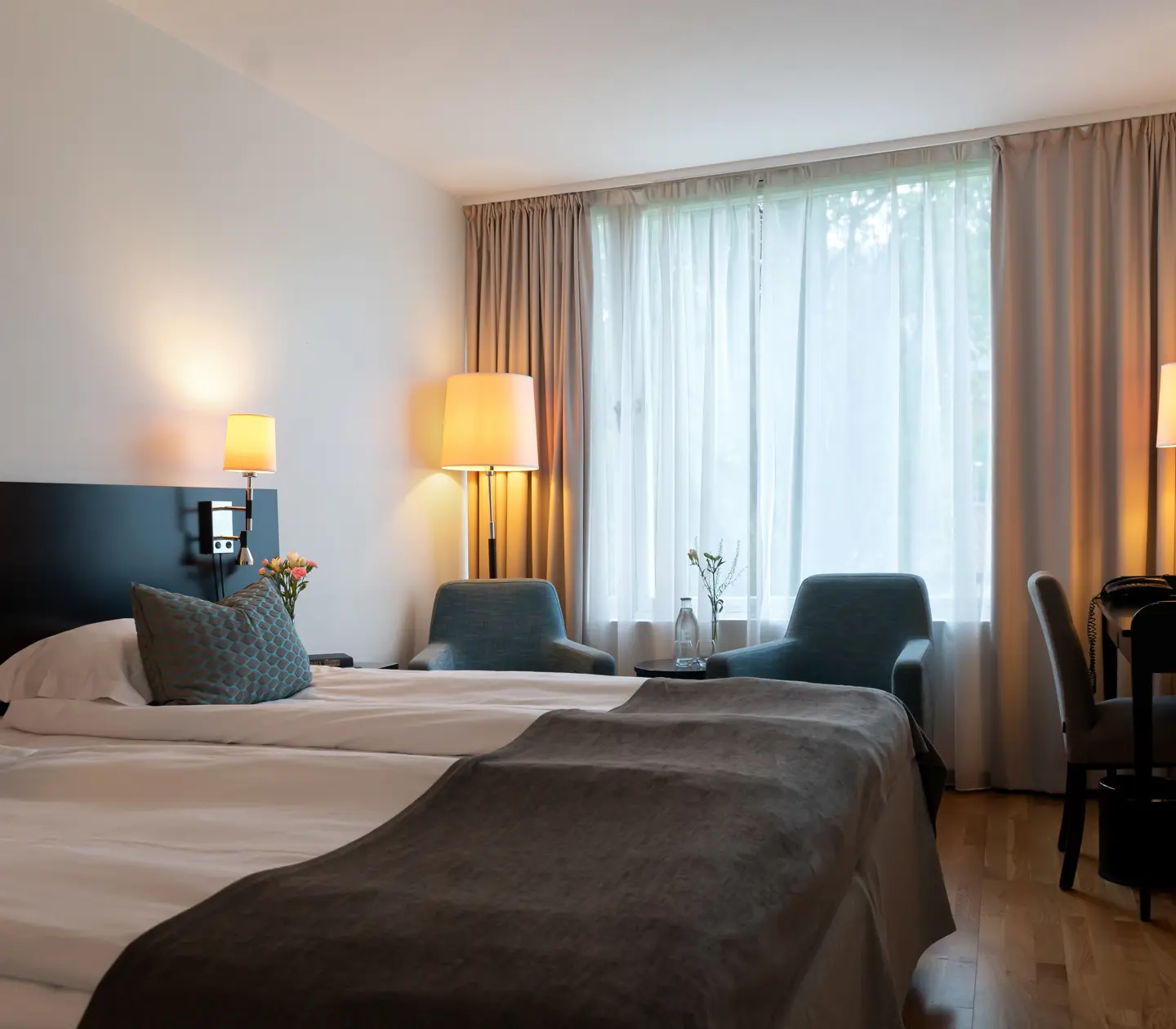 Hotel room with bed, desk and armchairs