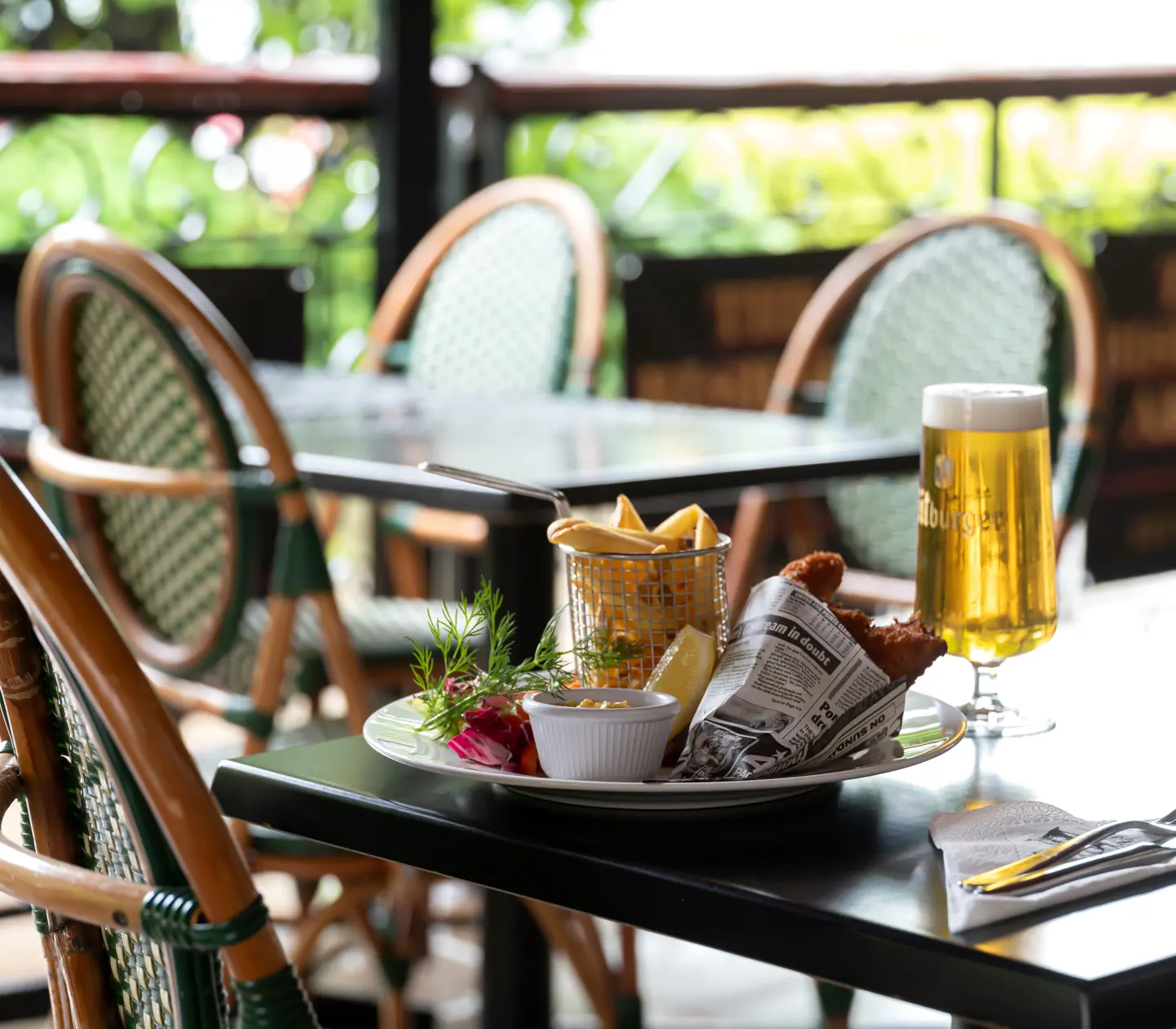Fish and chips served on the table with a glass of beer on the outdoor terrace