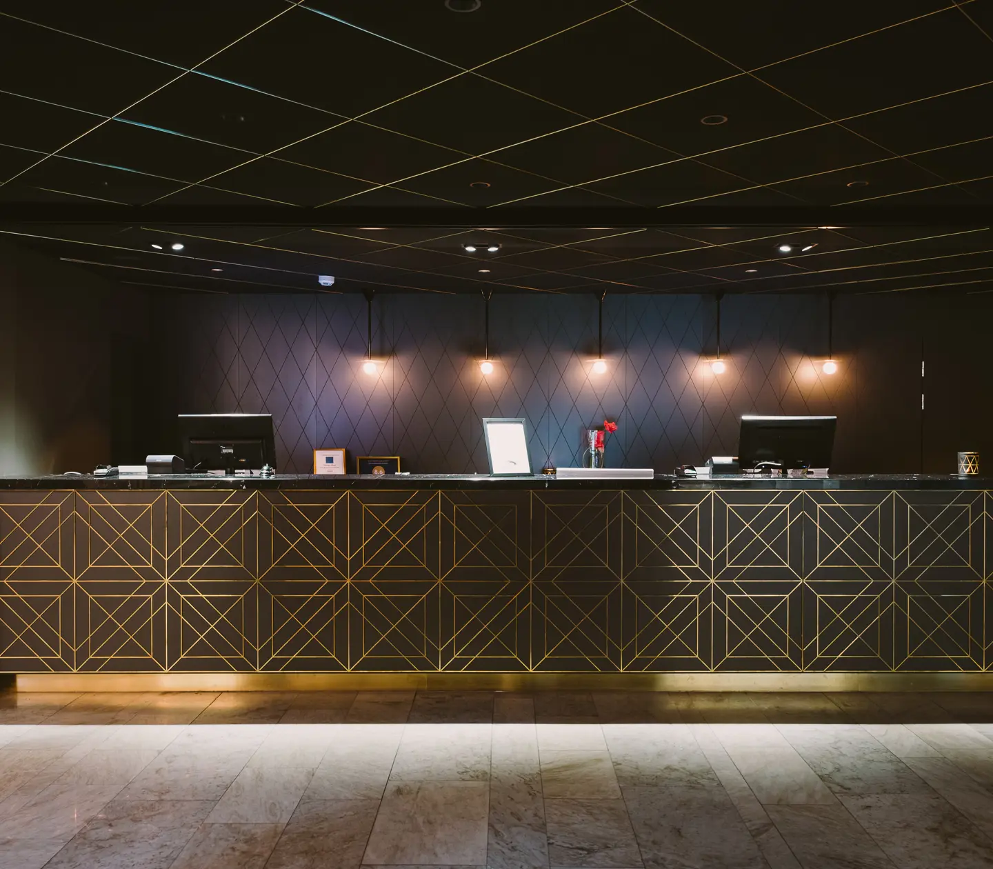Hotel lobby with reception desk with golden details and black ceiling
