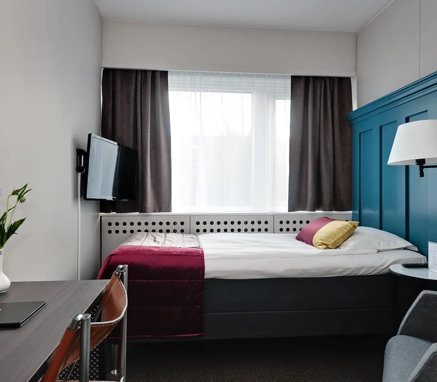 Colorful hotel room with single bed with large blue headboard