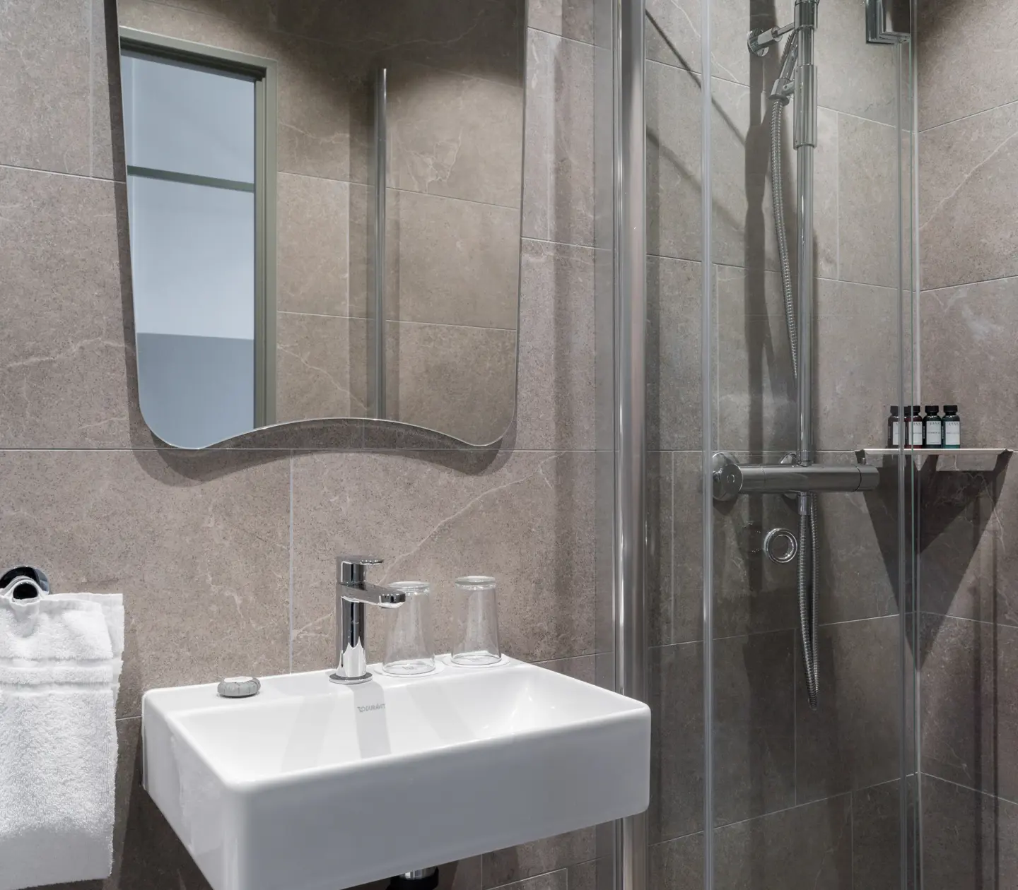 Beige bathroom with shower, sink and mirror