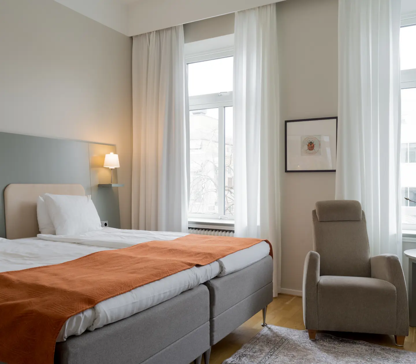 Bright hotel room with double bed, armchair and window