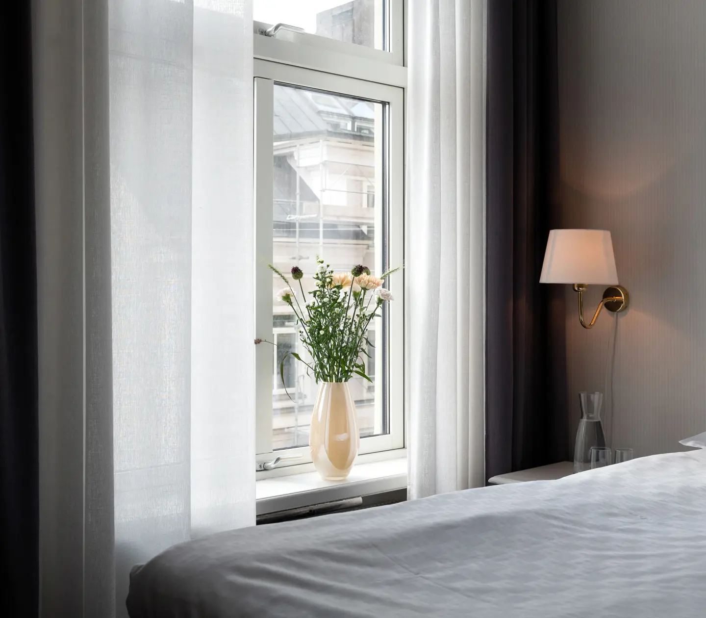 Bright hotel room with double bed, window and bouquet
