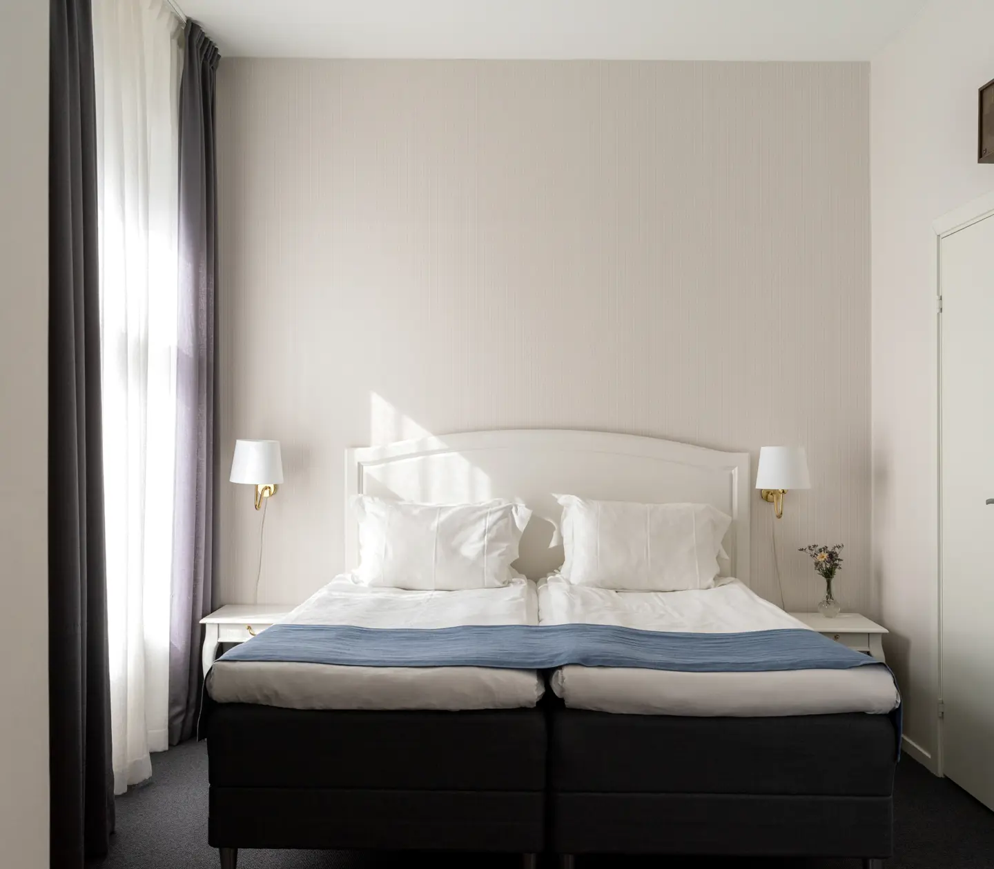 Bright hotel room with double bed, window and bedside lamps