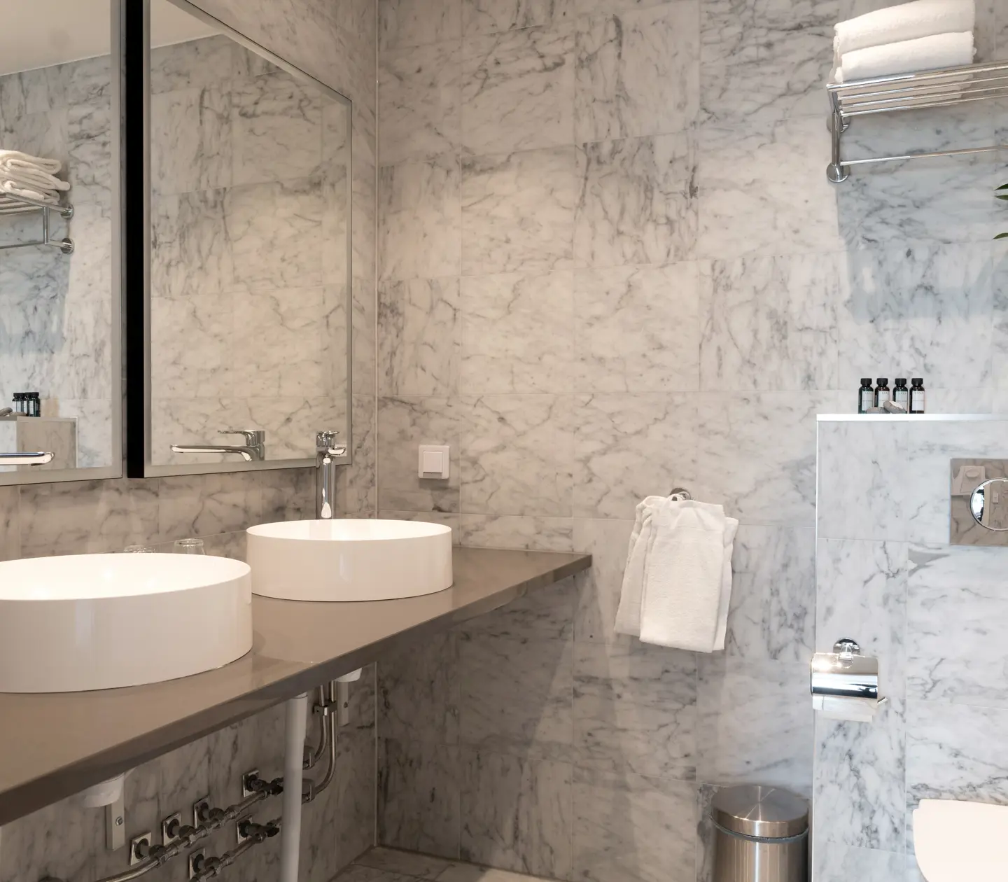 Bright bathroom with double sinks, toilet and mirrors