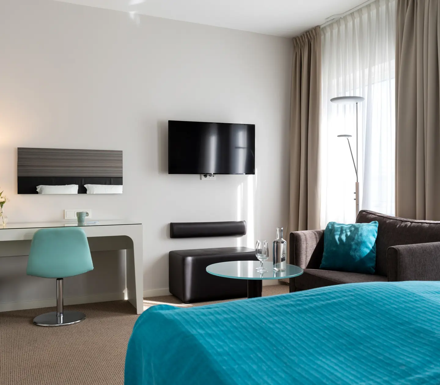 Hotel room with double bed, desk, armchair and TV