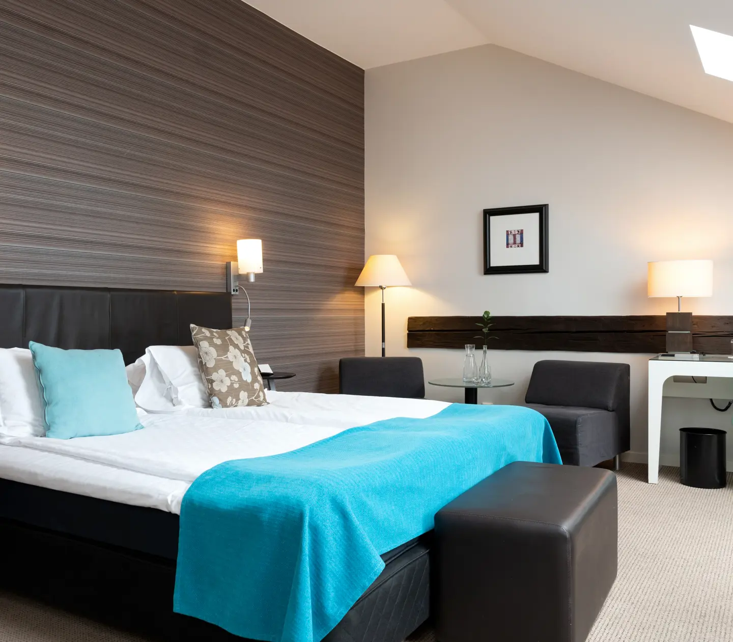 Hotel room with slanted ceiling, double bed and desk