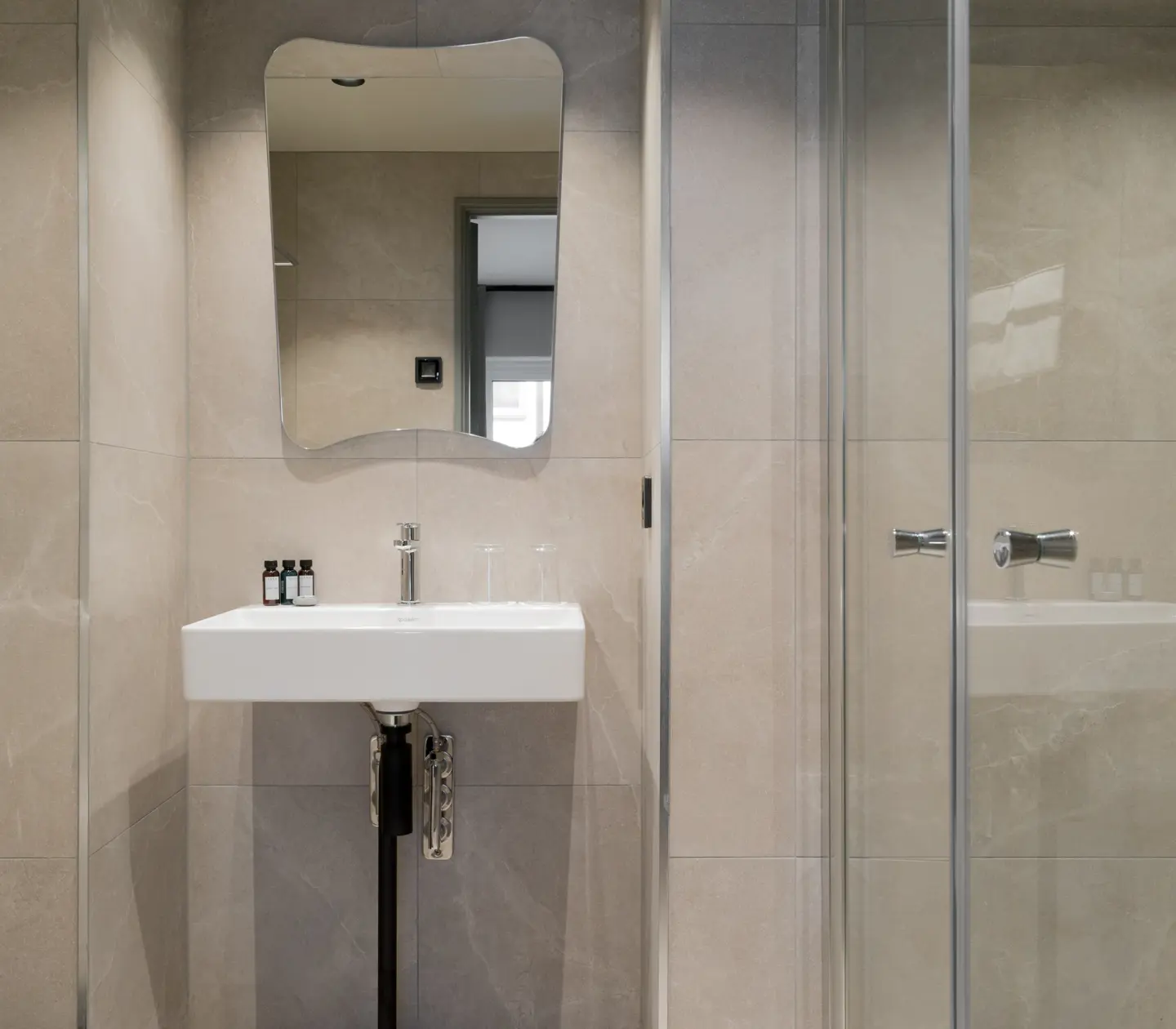 Beige bathroom with shower, sink and mirror