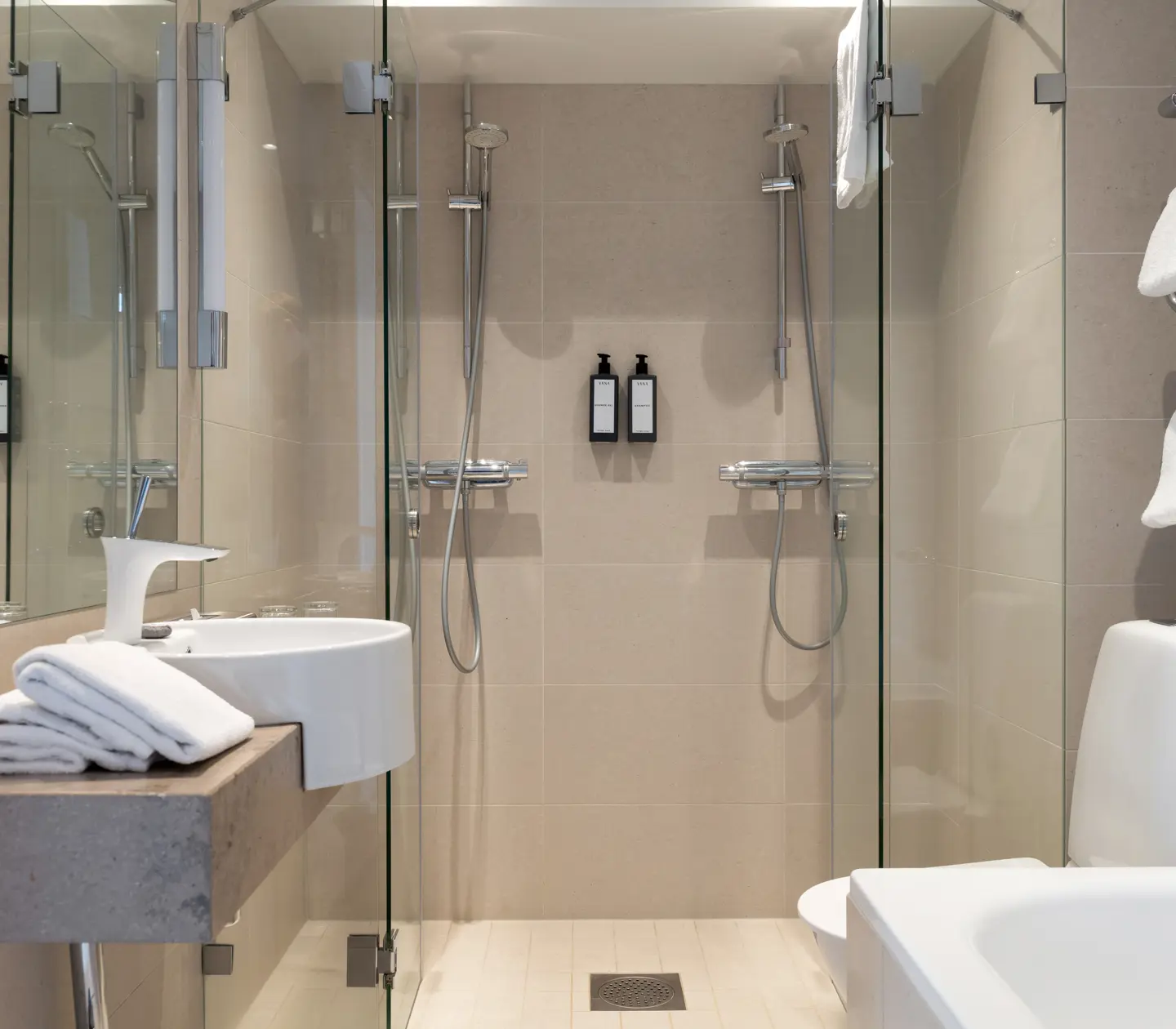 Beige bathroom with bathtub, sink and double showers