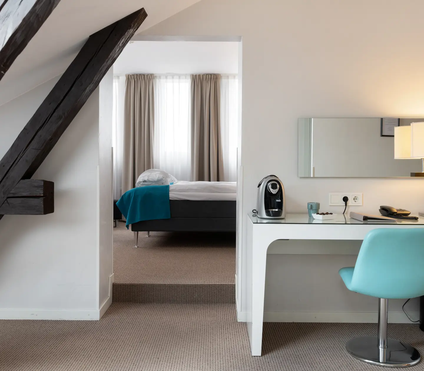 Bright suite with desk, ceiling beams and bed