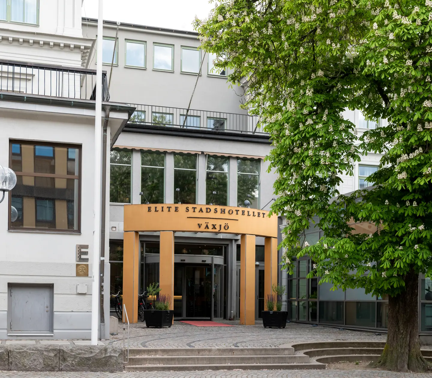 The facade of the Elite Stadshotellet in Växjö with a large tree outside