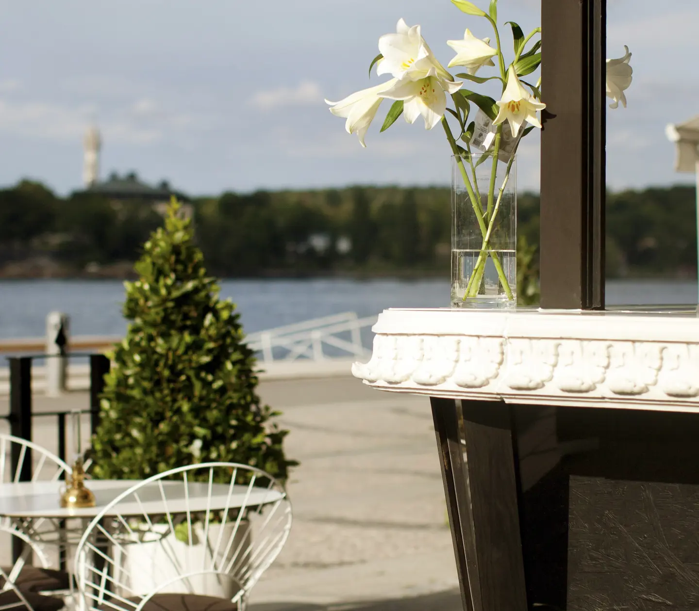 Uteservering vid vattnet med blommor och utsikt över en ö i Sverige