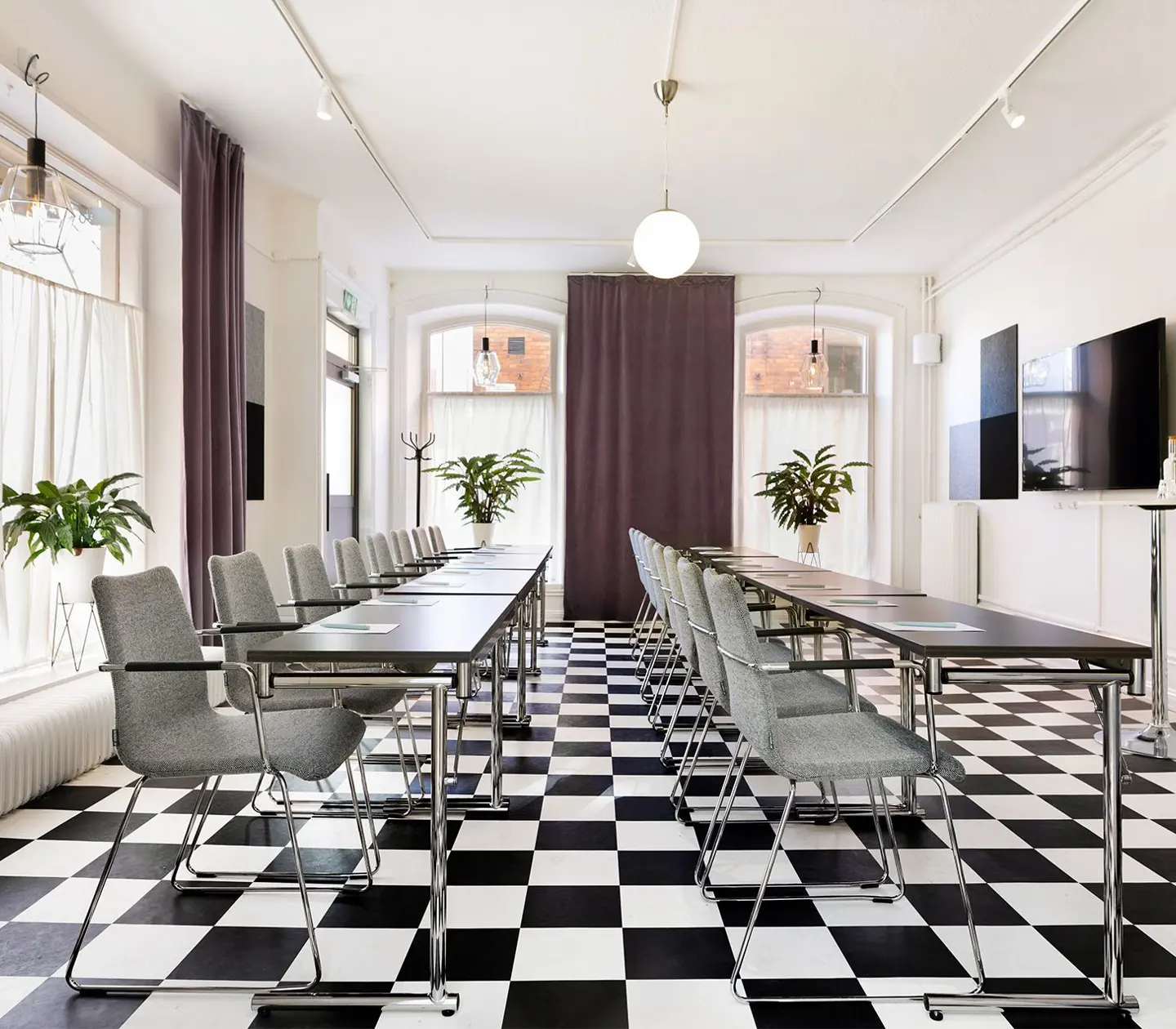 Konferensrum med schackrutigt golv, stolar och stora fönster