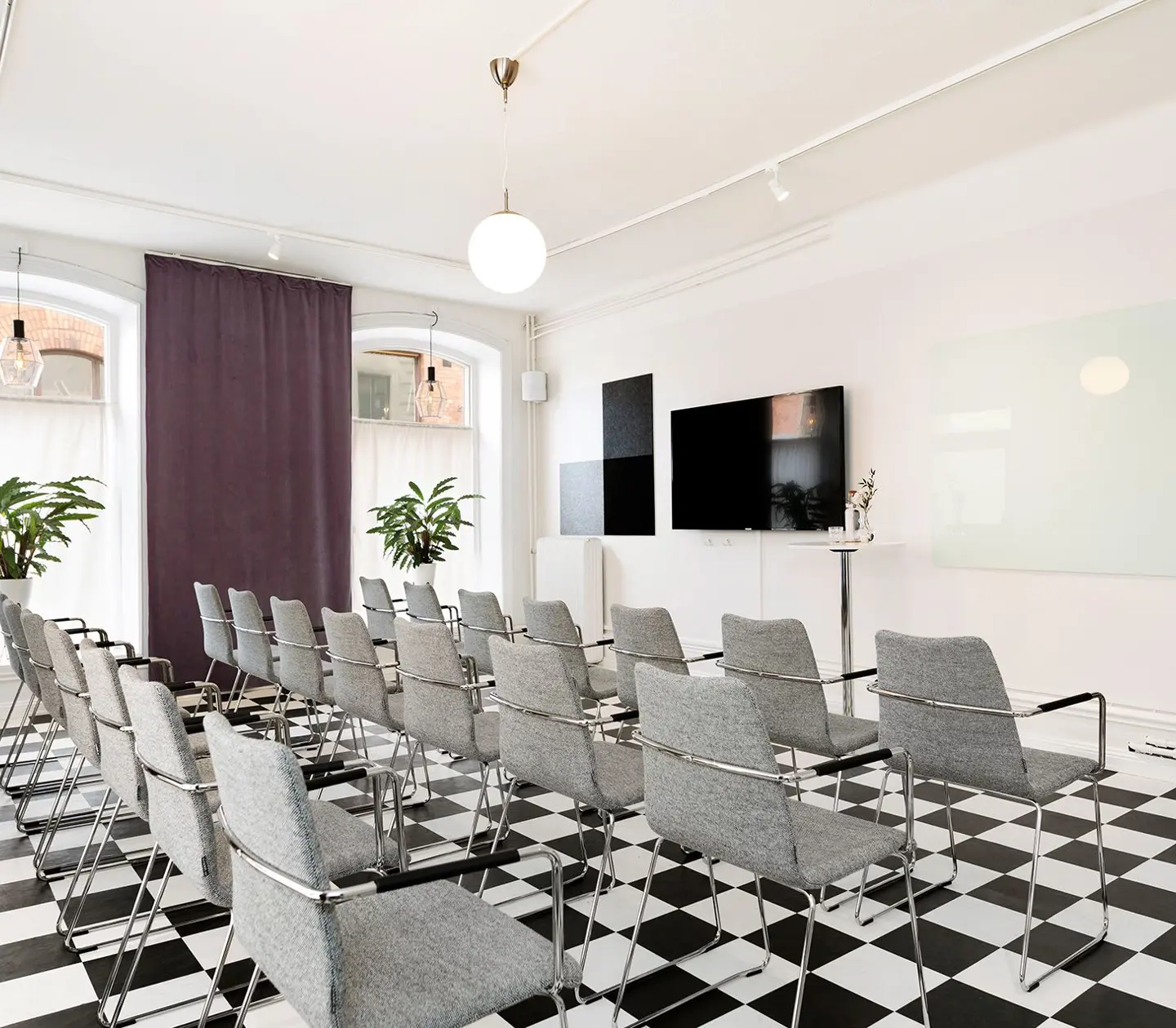 Konferensrum med schackrutigt golv, stolar och stora fönster