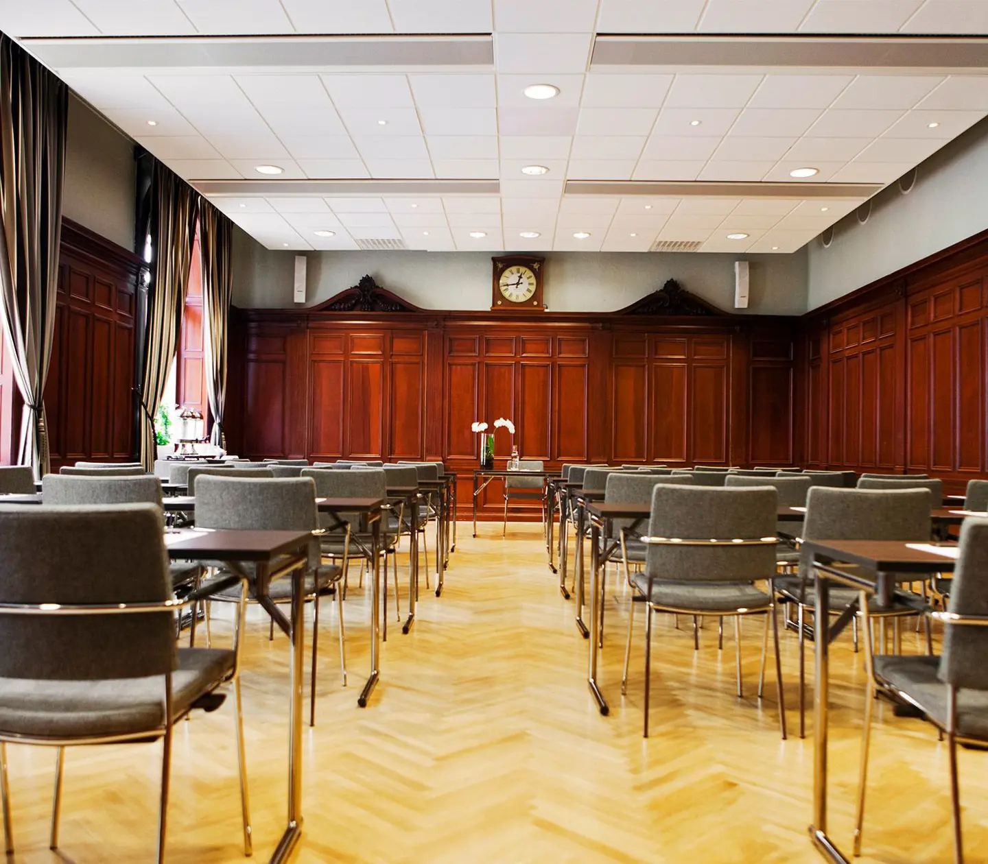 Röd konferenssal med många stolar, bord och fönster