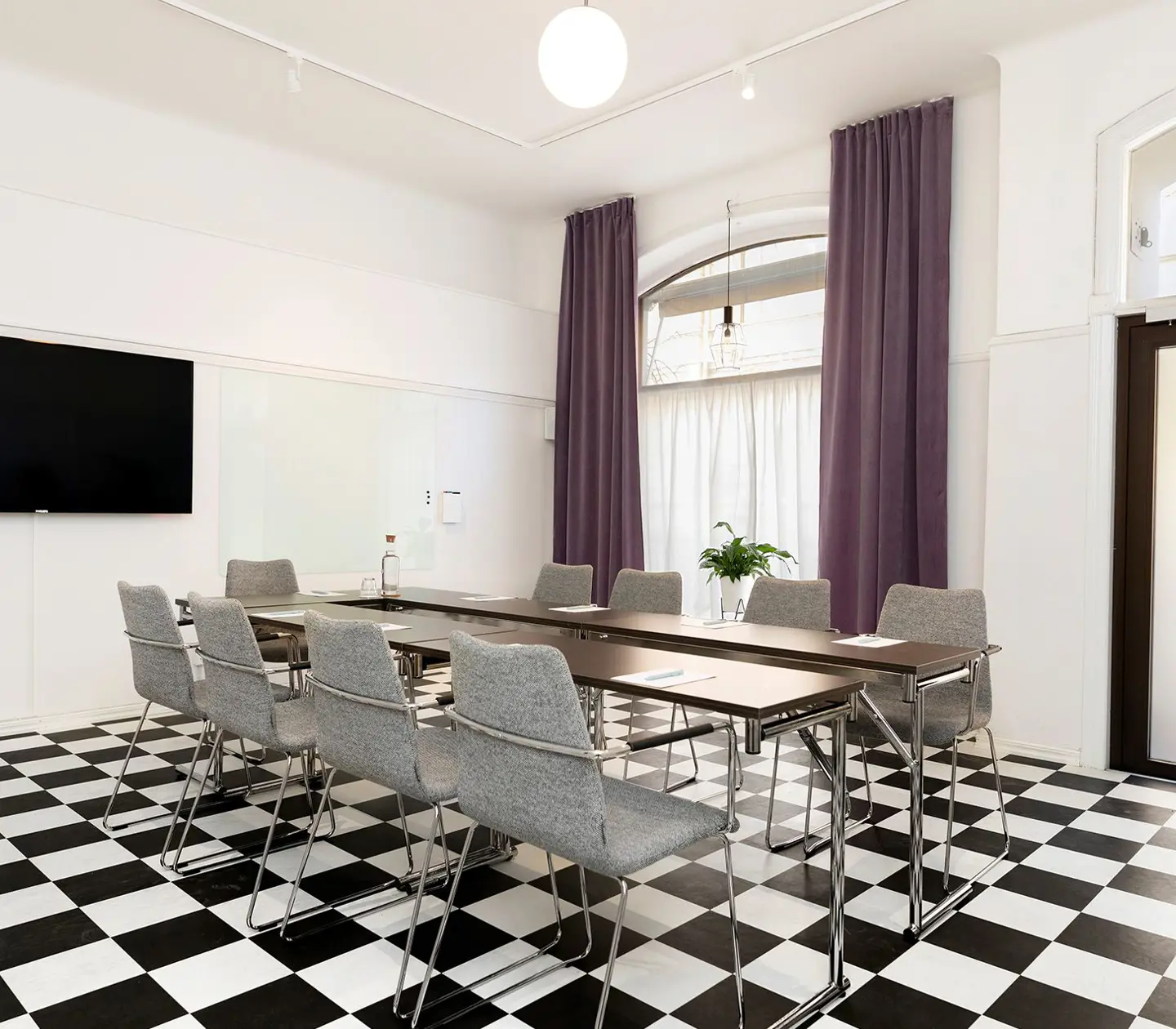 Konferensrum med schackrutigt golv, bord och stolar