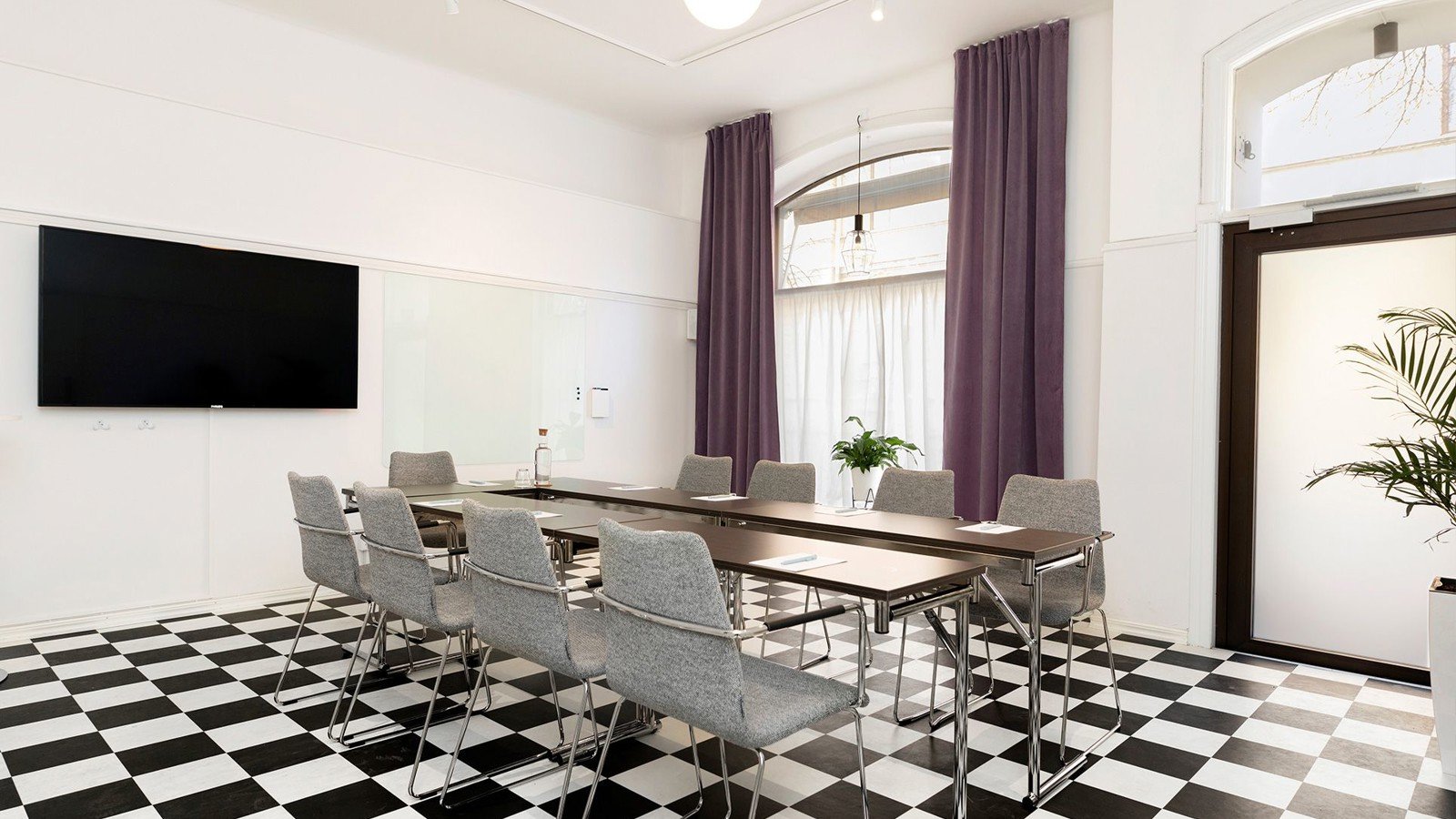 Konferensrum med schackrutigt golv, bord och stolar