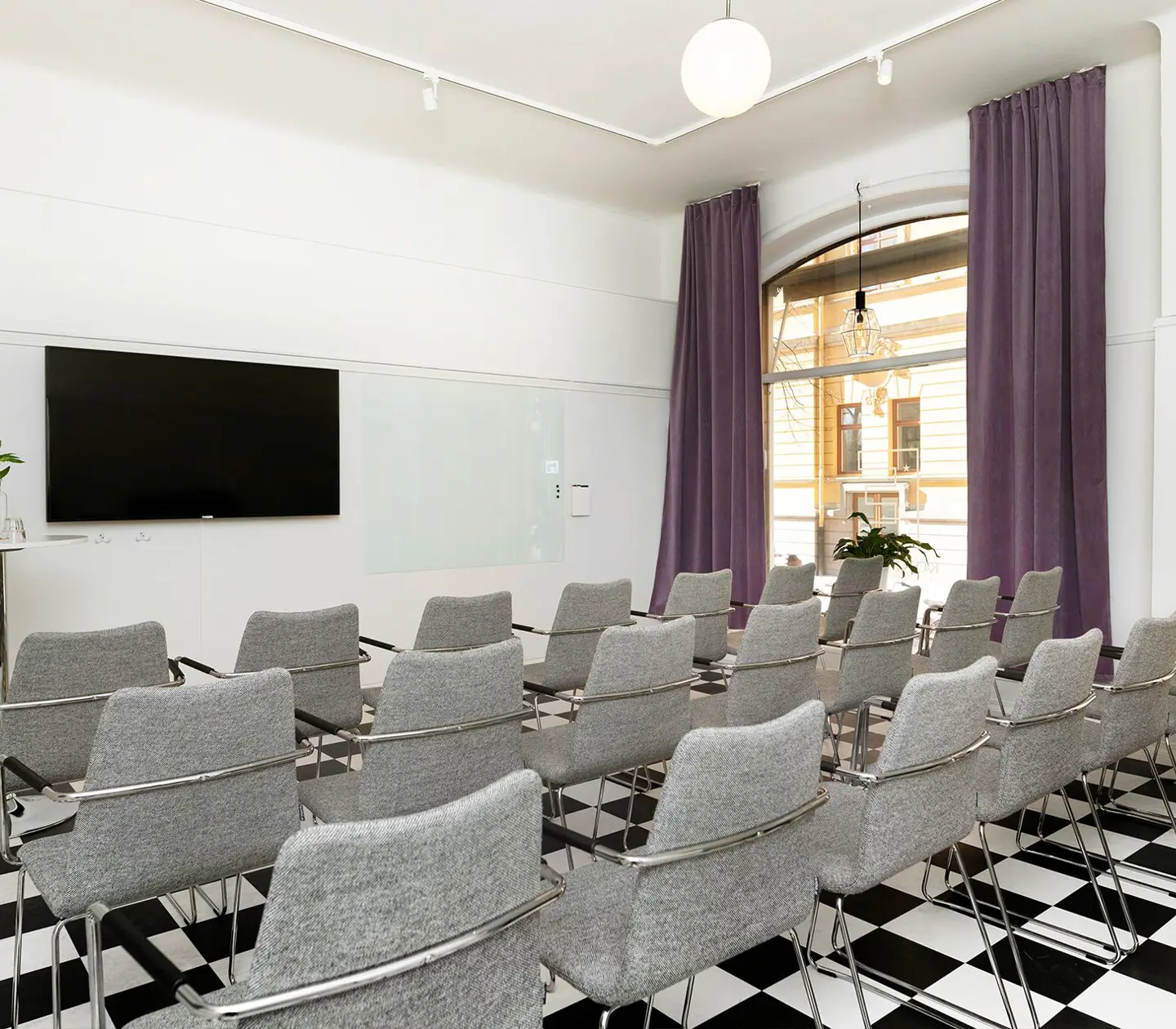 Konferensrum med schackrutigt golv, stolar och stort fönster