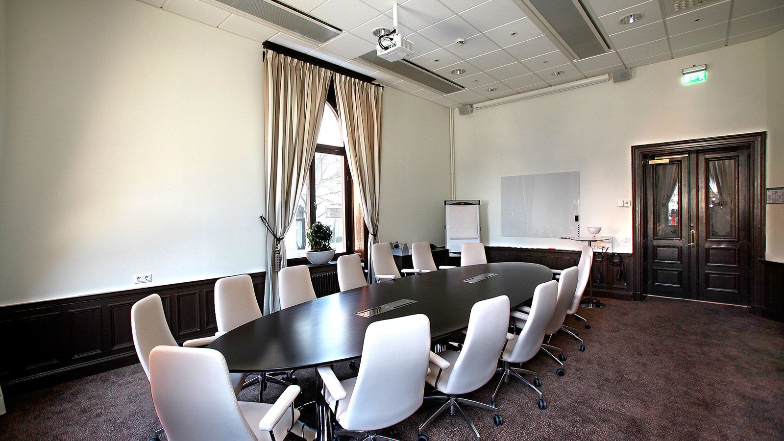 Konferenssal med runt bord, stor dörr och fönster