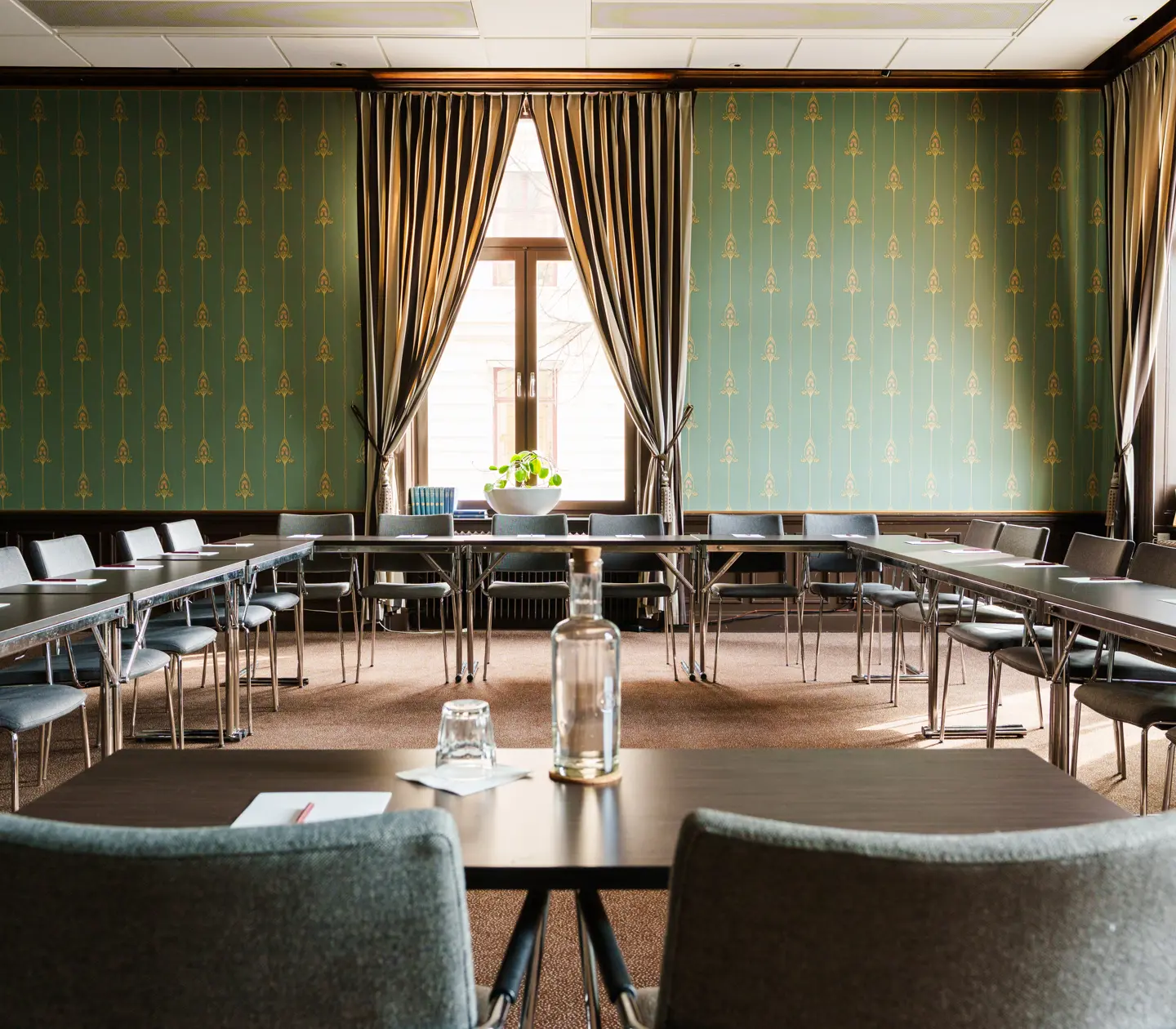 Fin konferenssal med bord, stora dörrar och fönster