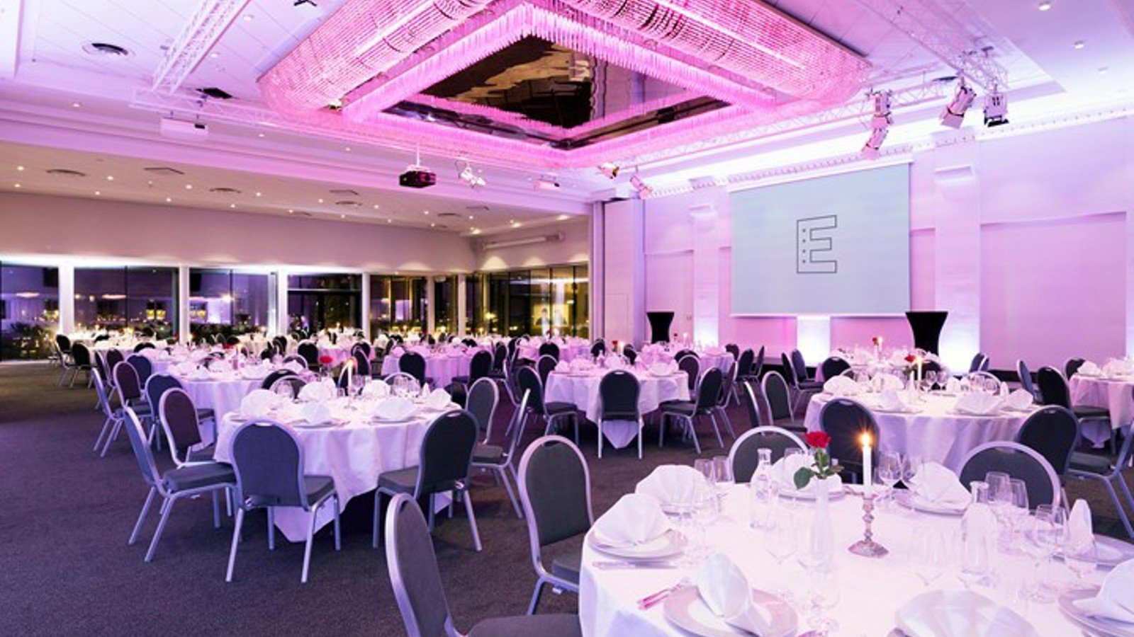 Event with round tables and pink lighting