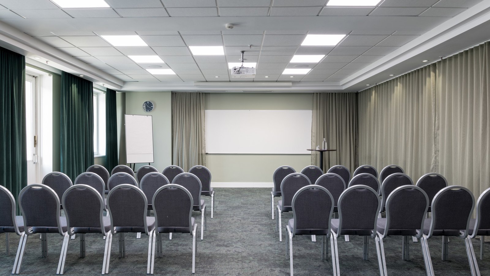 Fint konferensrum med stolar i rader, gardiner och whiteboard