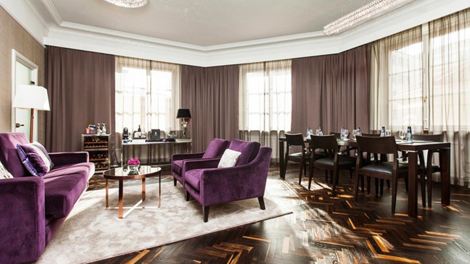 Rum med lila soffa och fåtöljer, samt skrivbord och konferensbord