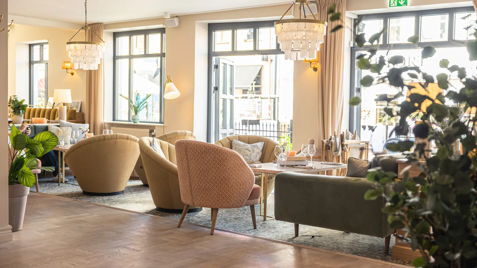 Elegant lobby with nice light, modern furniture, wooden floor and hanging chandeliers.
