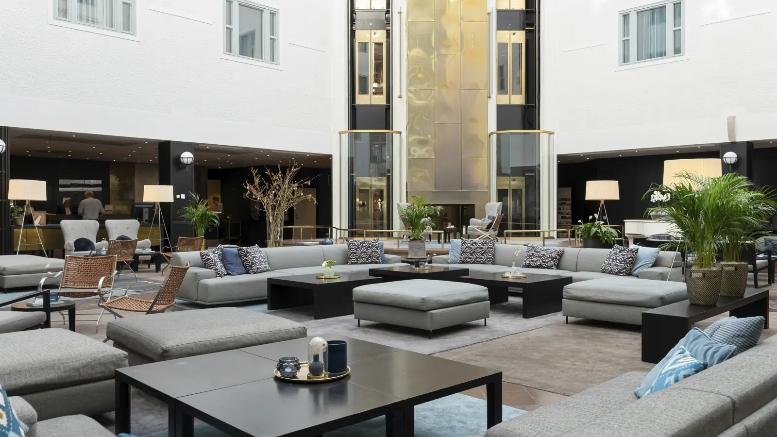 Elegant and spacious hotel lobby with modern decor, seating areas in a neutral color scheme and natural light.