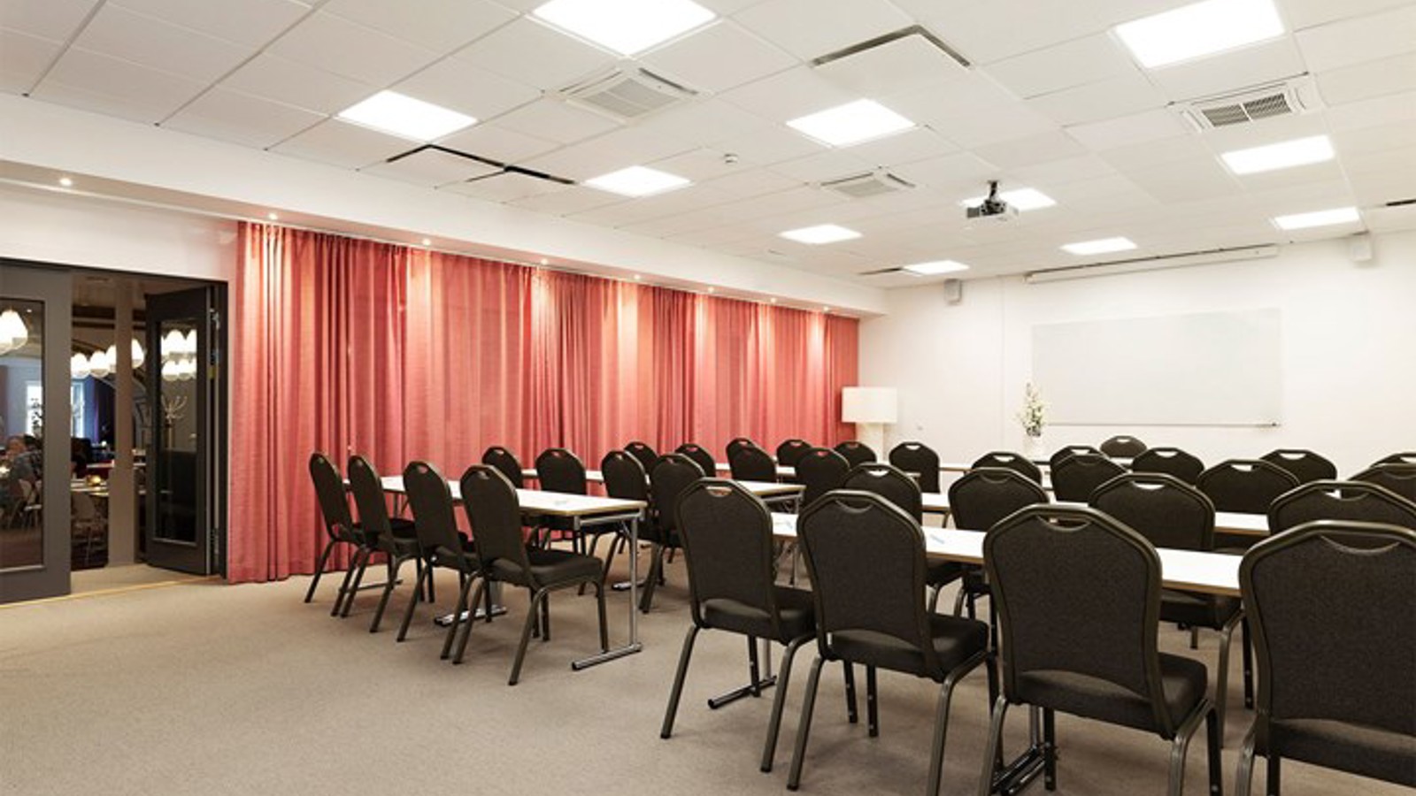 Konferensrum med skolsittning, rött draperi, ljusa väggar