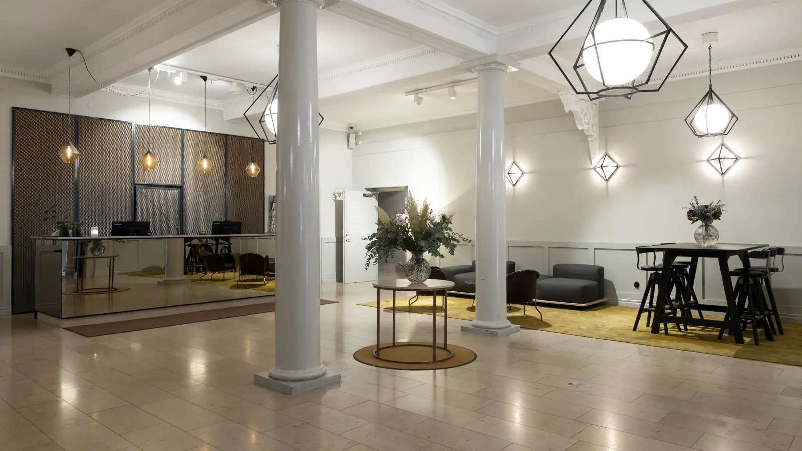 Modern hotel lobby with elegant lighting, a mirrored front desk, contemporary seating area, and stylish decor for a welcoming atmosphere.