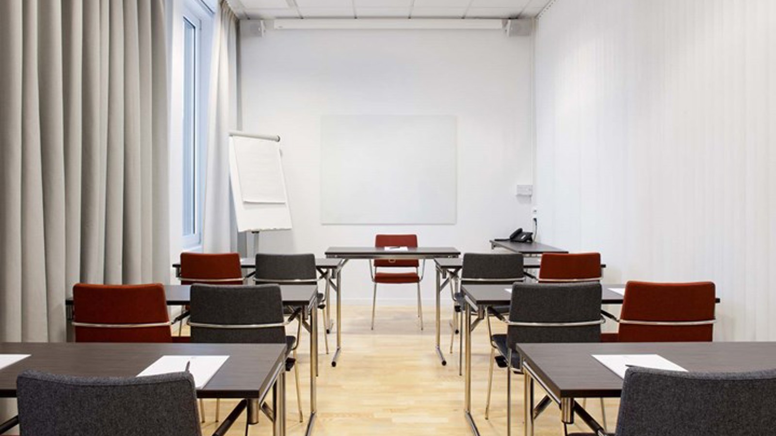 Konferensrum med skolsittning, svarta bord, vita väggar