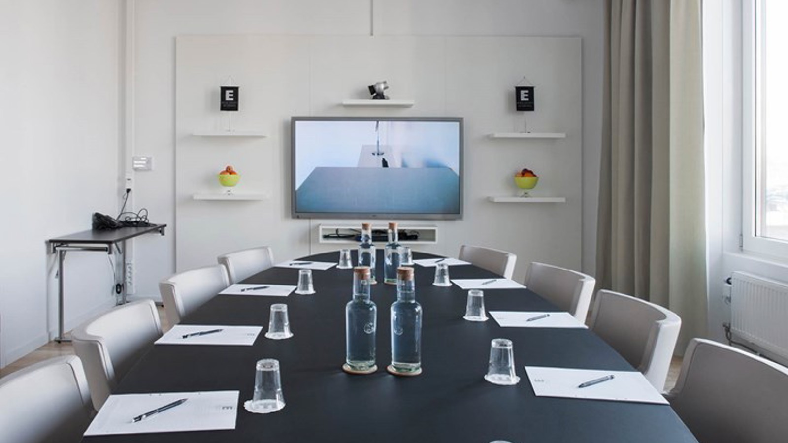 Konferensrum med styrelsesittning, svart bord, vita väggar