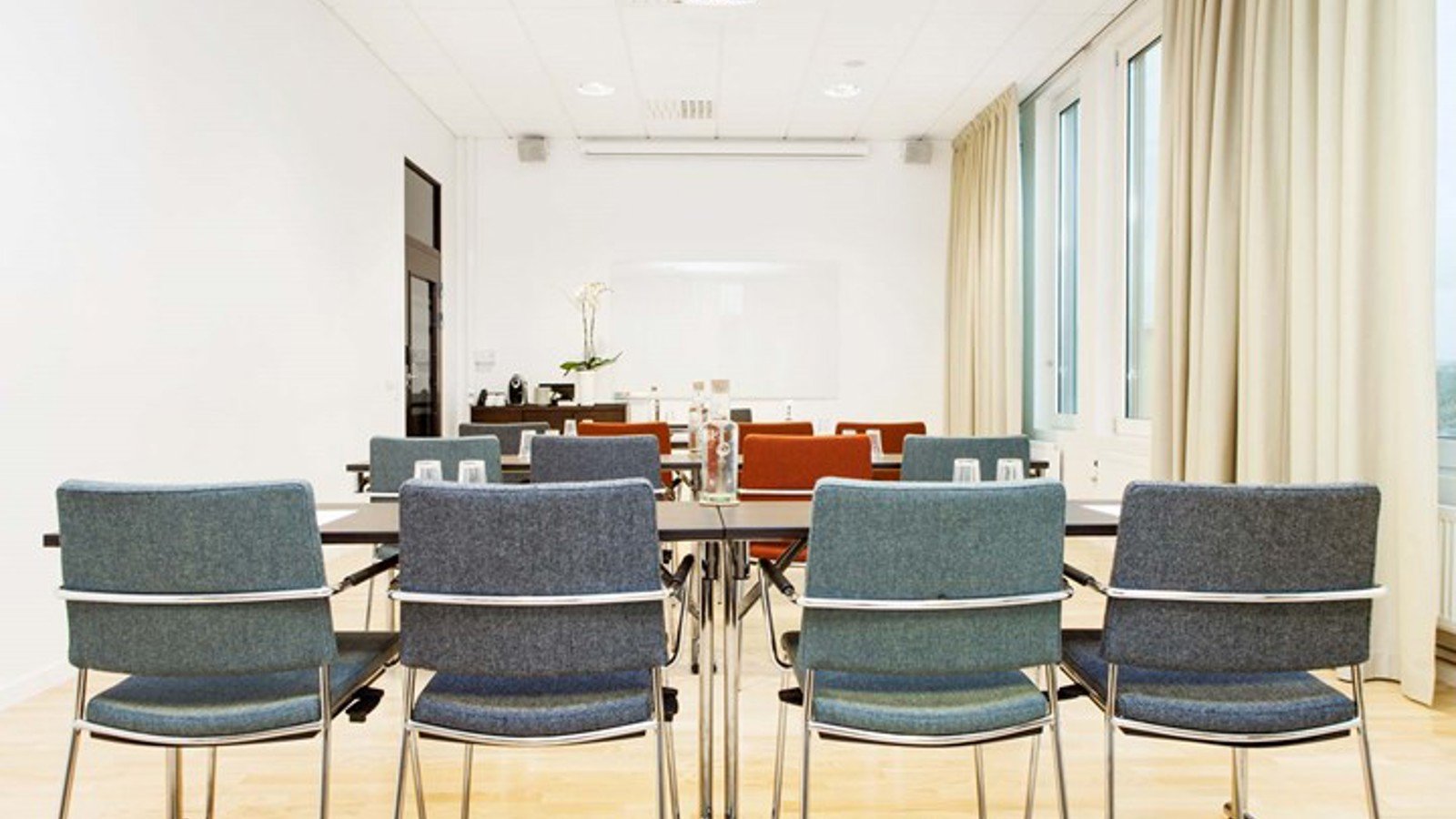Konferensrum med skolsittning, grå stolar och vita väggar