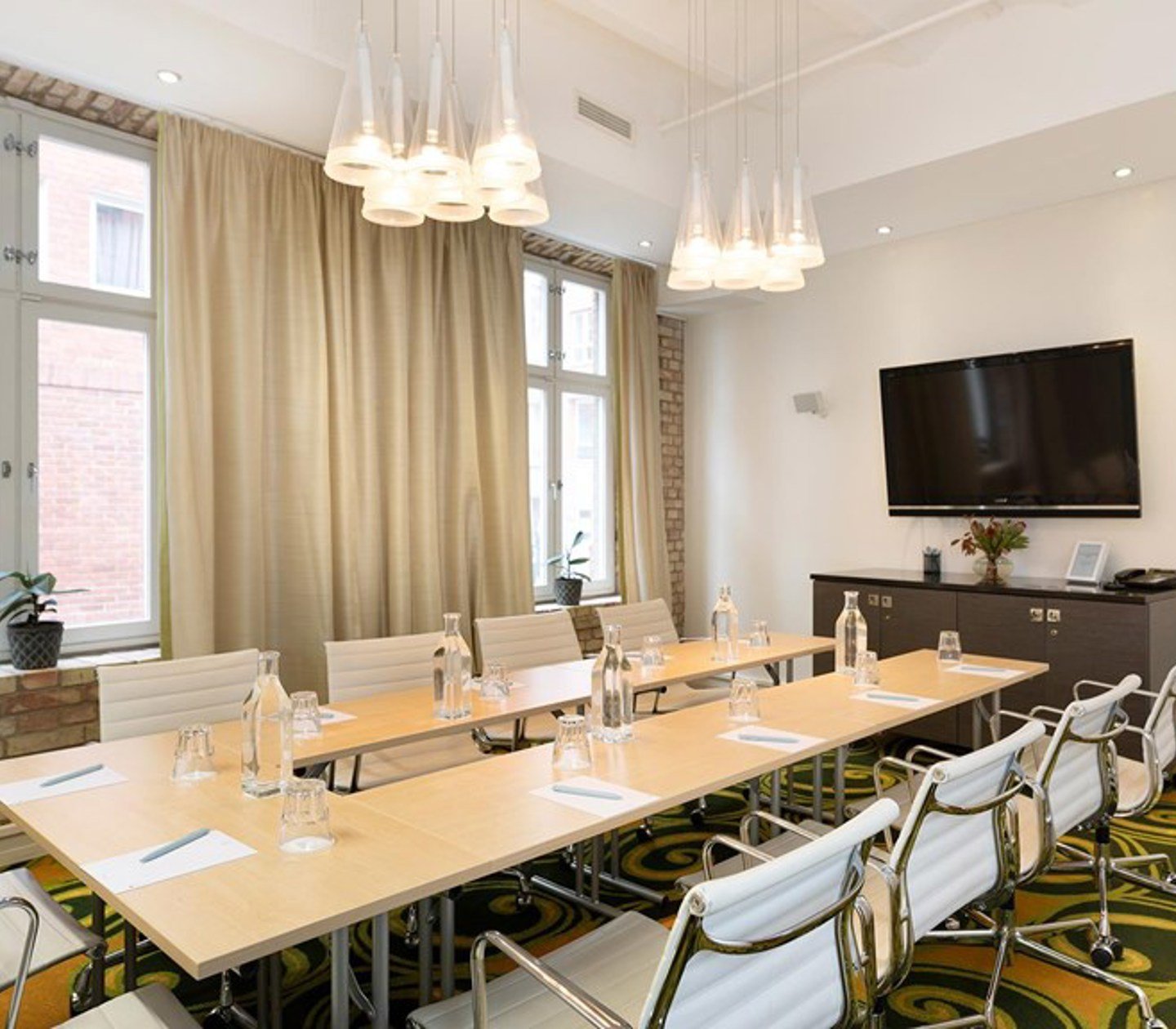 Konferensrum med styrelsesittning, ljusa väggar, grönmönstrad matta, stora fönster
