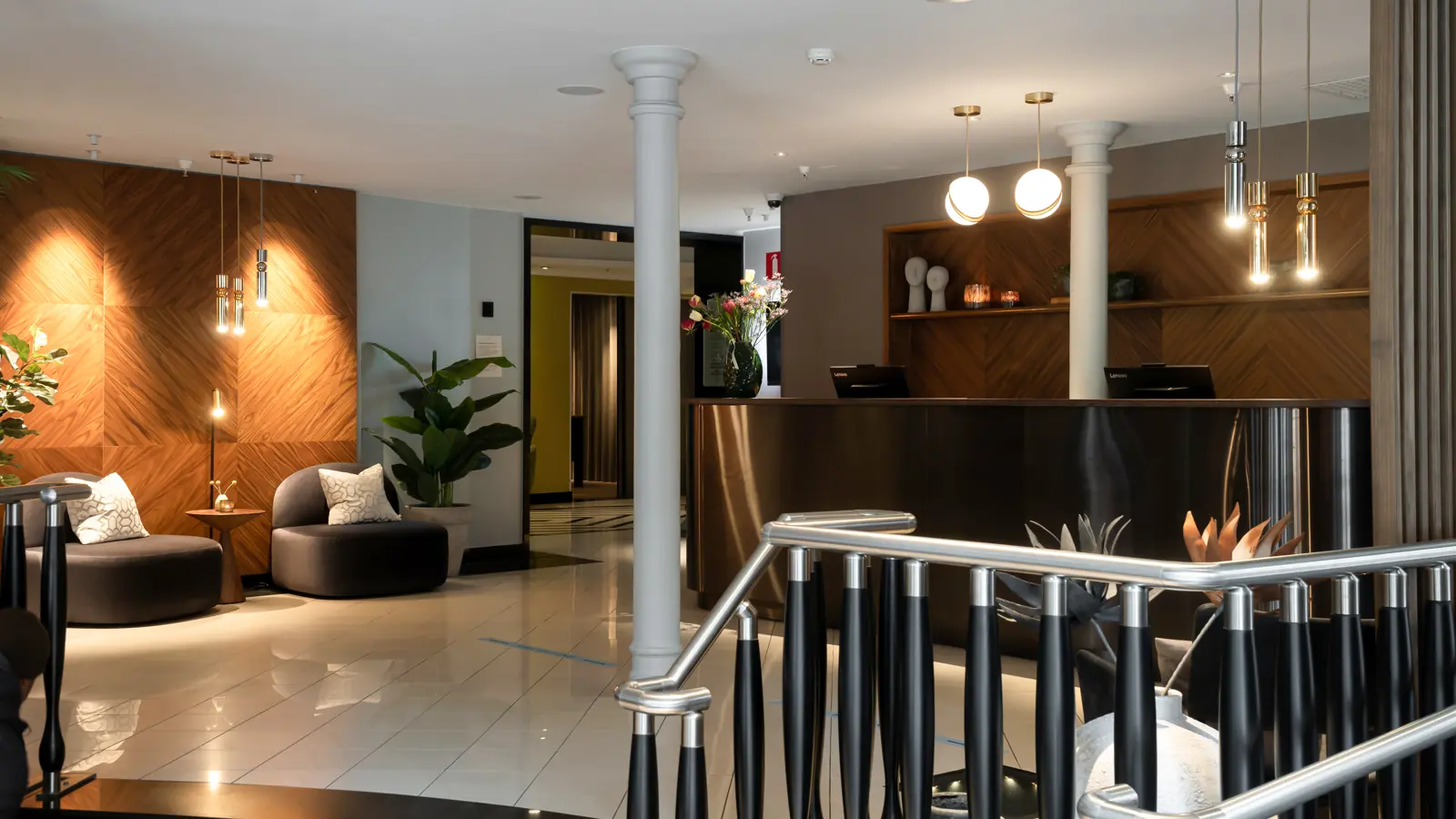 Modern hotel lobby with elegant reception desk, stylish seating, soft lighting, and decorative plants, creating a welcoming and sophisticated atmosphere.