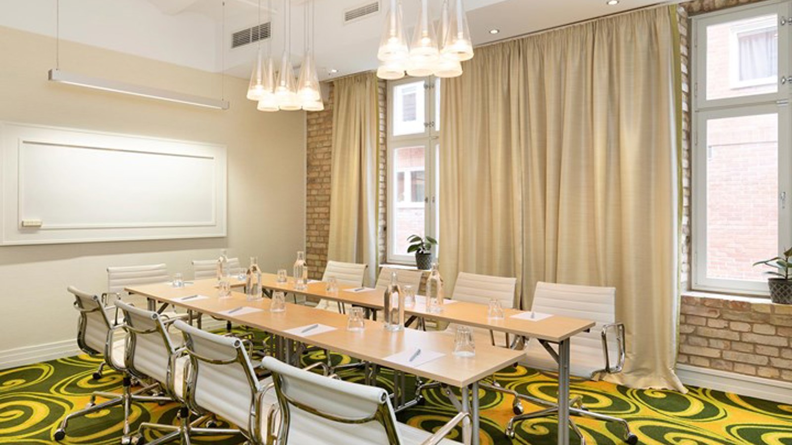 Konferensrum med styrelsesittning, ljusa väggar och grönmönstrad matta