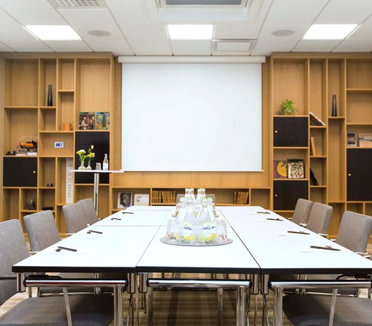 A conference table set up with pens, paper and sparkling water