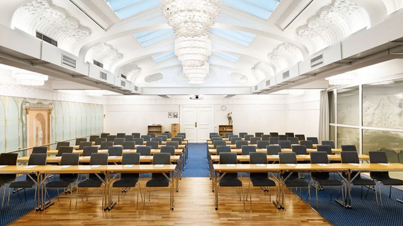 Stor konferenssal i biosittning med takfönster, stuckaturer och vita väggar
