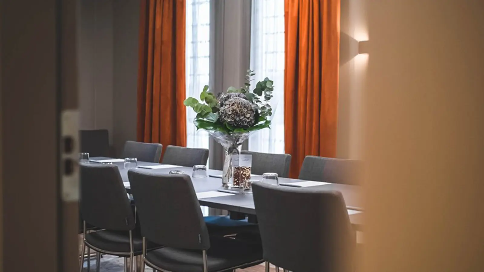 Board room with gray chairs and rust-brown curtains