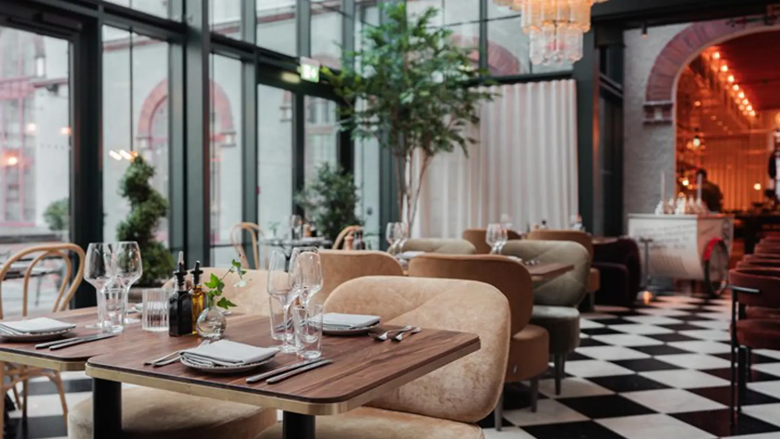 Restaurangmiljö med dukade bord, svart- och vitrutigt golv, stora fönster