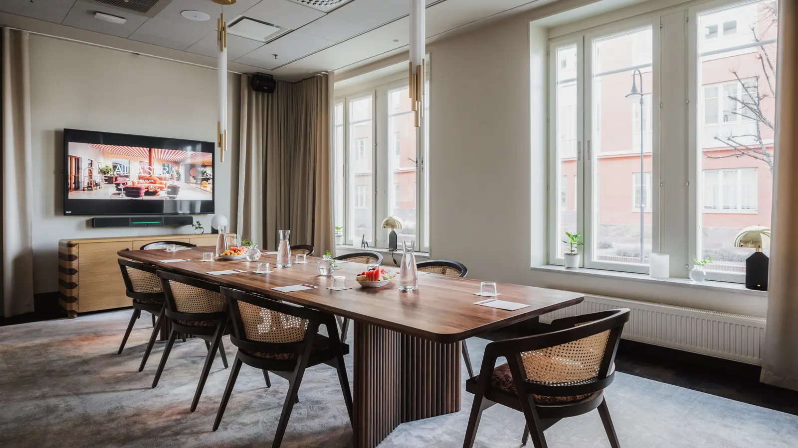 Board room with brown table, large windows and TV screen