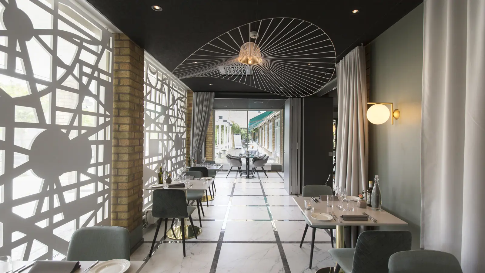 Modern restaurant interior with geometric wall patterns, elegant lighting, marble flooring, and minimalist table settings.