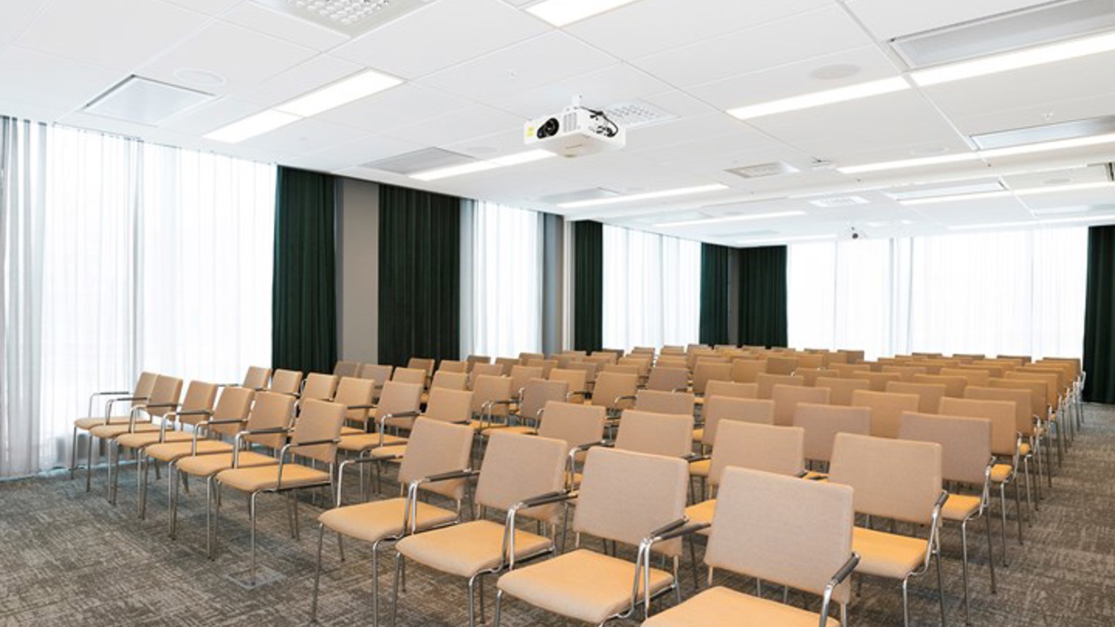 Konferensrum med biosittning, ljusbruna stolar, grått golv vita draperier 