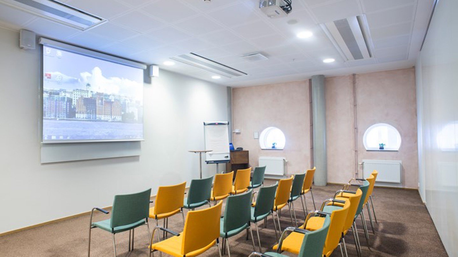 Conference room with cinema seating, yellow and blue chairs, white walls and a projector